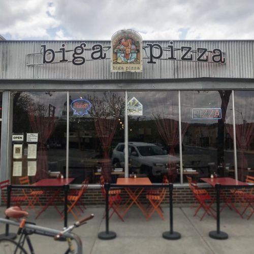 Exterior of Biga Pizza restaurant with outdoor seating, large windows, and a sign featuring the restaurant's name.