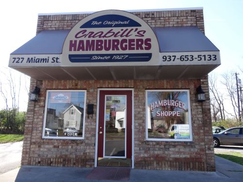 Exterior of Crabill's Hamburgers, a brick building with a sign and large windows displaying "Hamburger Shoppe."