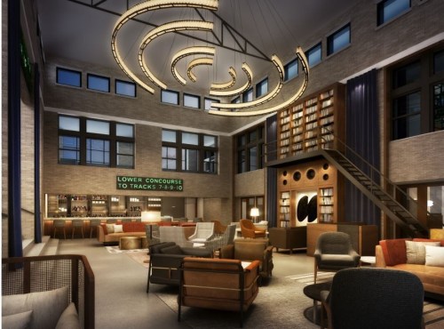 Modern lounge with high ceilings, stylish furniture, a large chandelier, and a bookshelf in a warm, inviting atmosphere.
