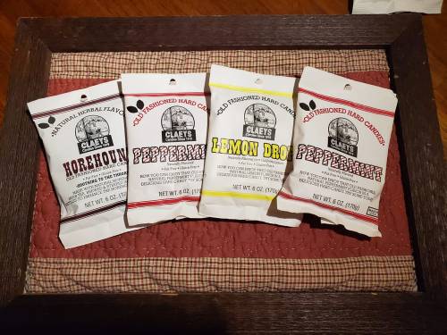 Four bags of Claey's old-fashioned hard candies: Horehound, Lemon Drop, and two Peppermints, displayed on a quilted background.