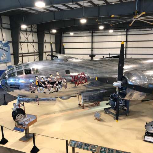 A vintage aircraft displayed indoors, featuring a shiny silver exterior and artwork depicting characters on the side.