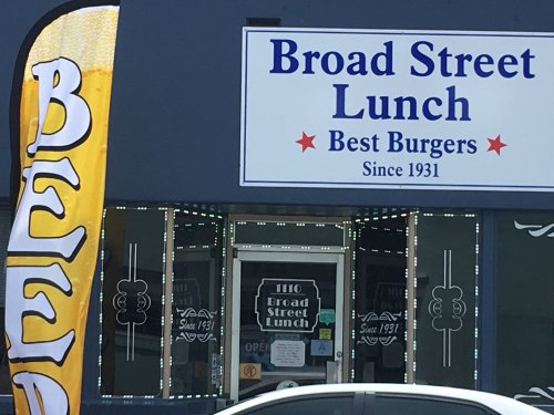 Sign for Broad Street Lunch, featuring "Best Burgers Since 1931," with a colorful banner nearby.