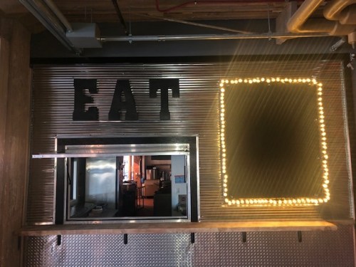 A restaurant window with the word "EAT" above it and a lighted empty frame beside it.