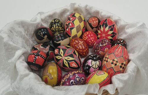 A basket filled with intricately decorated Easter eggs in vibrant colors and patterns.