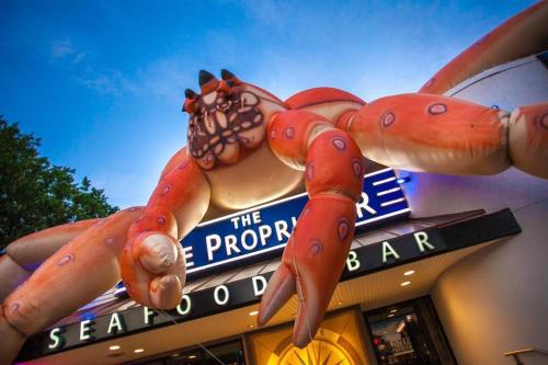 A large inflatable crab decorates the entrance of a seafood bar, with a blue sky in the background.