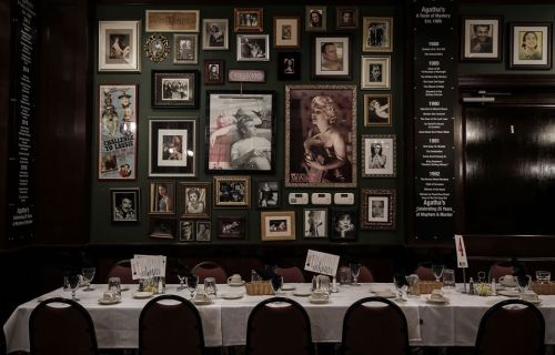 A dining table set with dishes in front of a wall adorned with various framed photos and memorabilia.