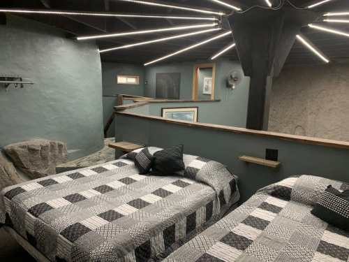 A cozy room with two beds, modern decor, and unique lighting features on the ceiling.