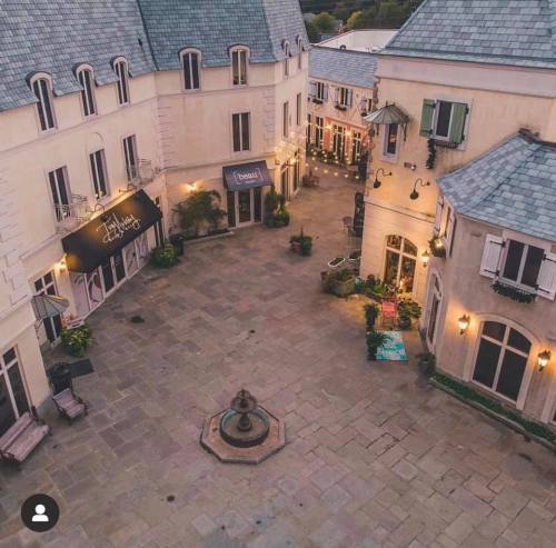 A charming courtyard with shops, a fountain, and decorative lighting, surrounded by elegant buildings.