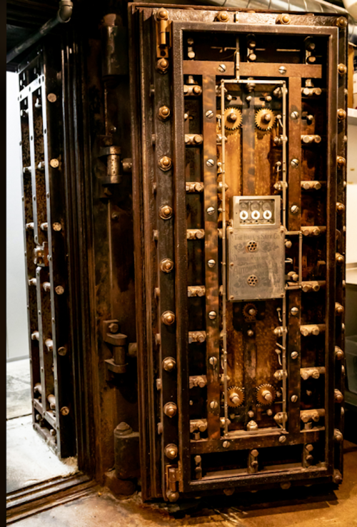 A large, ornate metal safe with intricate gears and a heavy door, showcasing a vintage design.
