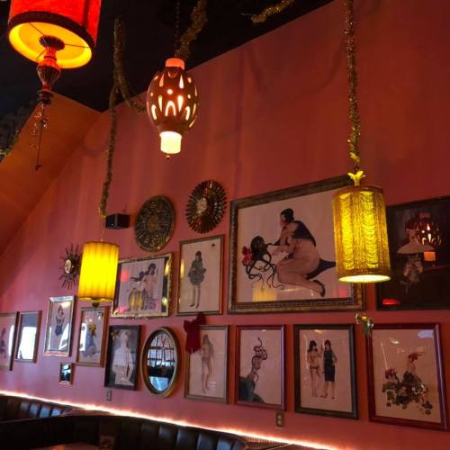Colorful wall adorned with framed art, vintage lamps, and festive decorations in a cozy, vibrant setting.