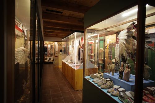 A museum hallway showcasing glass display cases filled with traditional artifacts and clothing.
