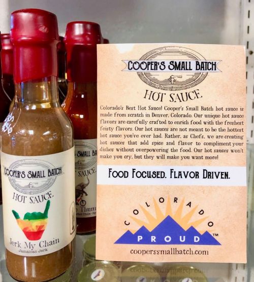 A display of Cooper's Small Batch hot sauces, featuring "Jerk My Chain" and a promotional card about their flavors.