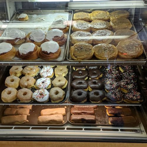 A display case filled with various donuts, including glazed, frosted, and sprinkled varieties.