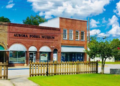 Exterior of the Aurora Fossil Museum, featuring a brick building with arched windows and a green lawn in front.