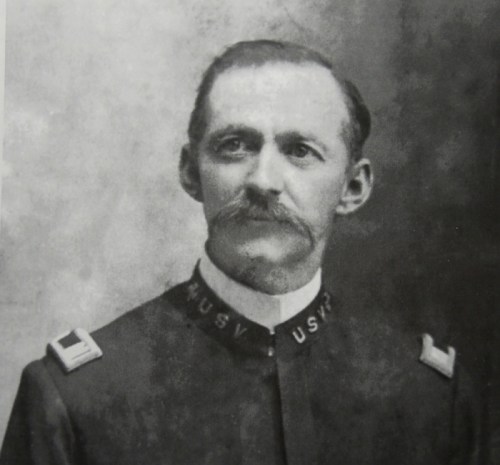 Black and white portrait of a mustached man in a military uniform with "USV" insignia on the collar.
