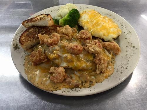 A plate of food featuring fried shrimp, cheesy casserole, broccoli, cauliflower, and toasted bread.