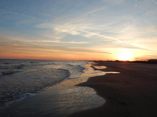 A serene beach at sunset, with gentle waves lapping at the shore and a colorful sky reflecting on the water.