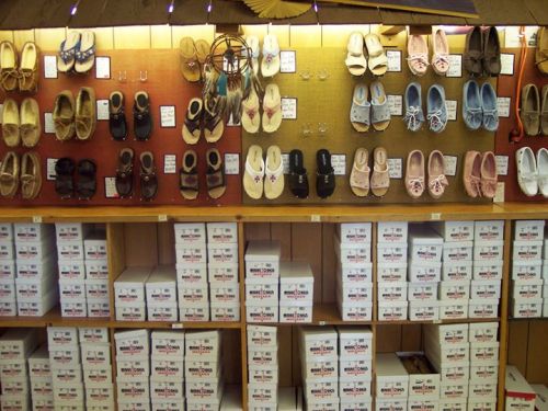 A display of various styles of shoes on a wall, with boxes of shoes stacked below.