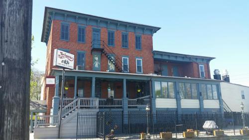 Historic brick building with a white porch, featuring a sign for "The Old Mill" and a staircase on the side.