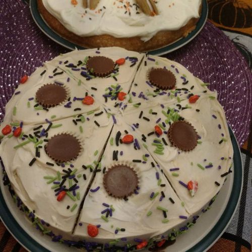 A decorated cake with frosting, chocolate candies, and colorful sprinkles, sliced into pieces on a festive table.