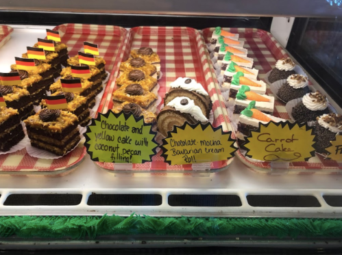 A display of assorted cakes, including chocolate, carrot, and mocha Bavarian cream, with colorful labels.