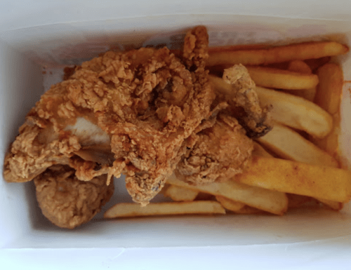 A box containing fried chicken pieces and golden French fries.