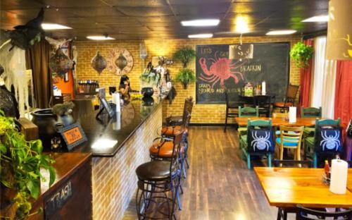 Cozy restaurant interior with a bar, brick walls, colorful chairs, and a chalkboard featuring a crab design.