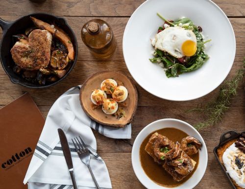 A spread of delicious dishes including a salad, shrimp, and a savory meat dish on a rustic wooden table.