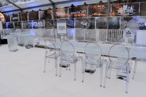 A winter-themed venue featuring ice tables and chairs, with a backdrop of ice sculptures and soft blue lighting.