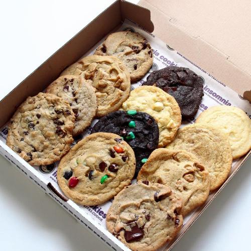 A box filled with assorted cookies, including chocolate chip, peanut butter, and colorful candy-topped varieties.
