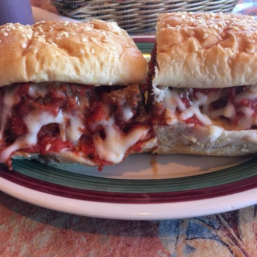 Two hearty sandwiches on a plate, filled with marinara sauce, melted cheese, and crispy bread.