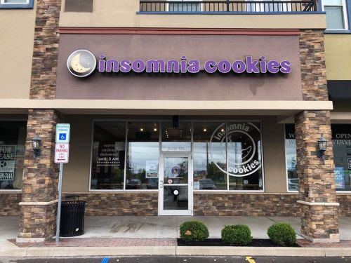 Exterior of an Insomnia Cookies store with a sign, featuring a logo and a welcoming entrance.