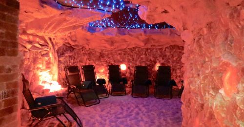 A tranquil salt cave with lounge chairs, illuminated by soft blue and orange lights, creating a relaxing atmosphere.