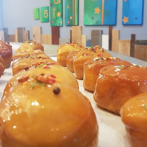 A close-up of glazed donuts topped with colorful sprinkles, arranged neatly on a table.