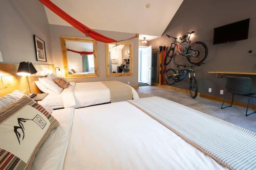 Cozy hotel room with two beds, a hammock, bikes on the wall, and a modern decor.