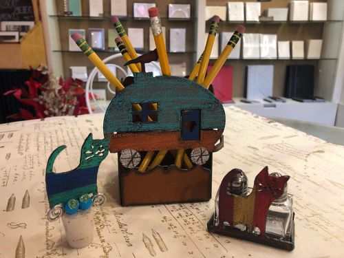 Colorful pencil holder shaped like a camper, with pencils and decorative cat figurines on a patterned table.