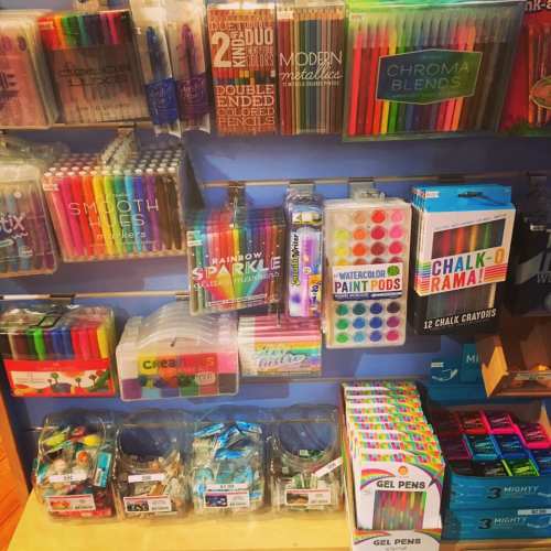 A colorful display of various art supplies, including markers, paint pods, gel pens, and chalk.