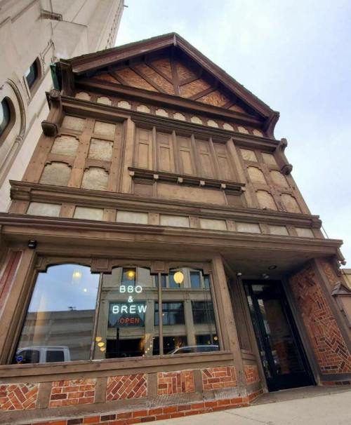 A historic building with a wooden facade and brick details, featuring a sign that reads "880 & Brew - OPEN."