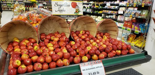 Baskets of SugarBee apples on display in a grocery store, with a sign indicating a special price of $3.49 per pound.