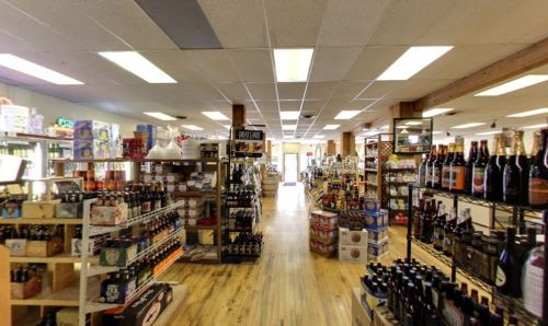 A spacious store aisle filled with shelves of various products, including beverages and snacks, under bright lighting.