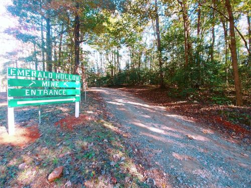 A gravel road leads to the entrance of Emerald Hollow Mine, surrounded by trees and greenery.