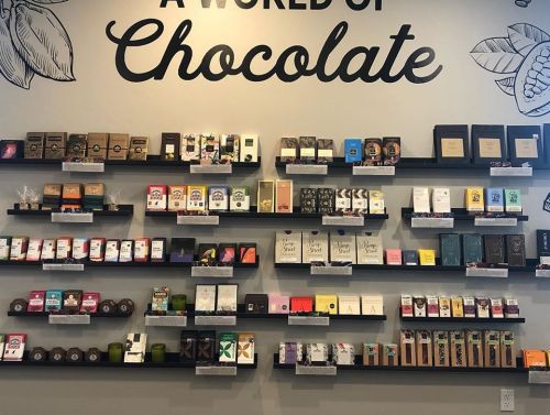 A wall display featuring various chocolate products on shelves, with a sign that reads "A World of Chocolate."