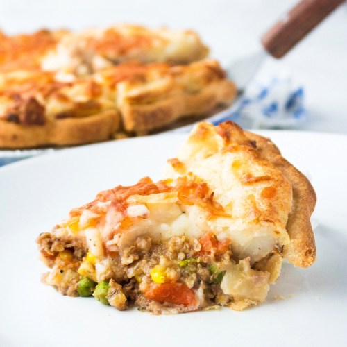 A slice of savory meat pie with a golden crust, filled with ground meat, vegetables, and topped with melted cheese.