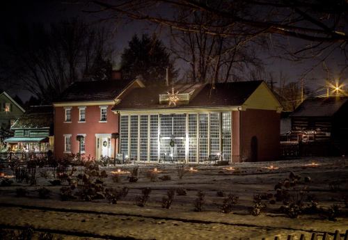 A cozy house at night, illuminated by soft lights, with a snowy yard and a star decoration on the roof.
