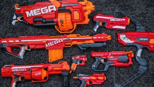 A collection of colorful toy blasters arranged on a dark textured surface, featuring various Nerf Mega models.