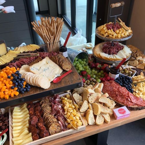 A beautifully arranged charcuterie board featuring cheeses, meats, fruits, crackers, and bread on a wooden table.