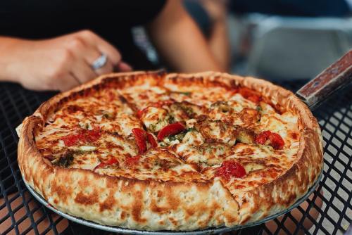 A close-up of a deep-dish pizza topped with pepperoni, sausage, and cheese, resting on a black table.