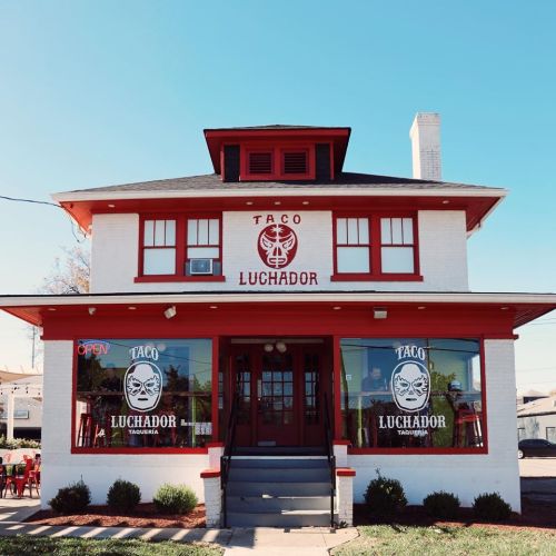 A red and white restaurant building with "Taco Luchador" signage and an open sign in the window.