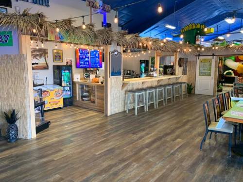 A tropical-themed café with a bar, seating, and colorful decor, featuring a playful atmosphere and bright lighting.