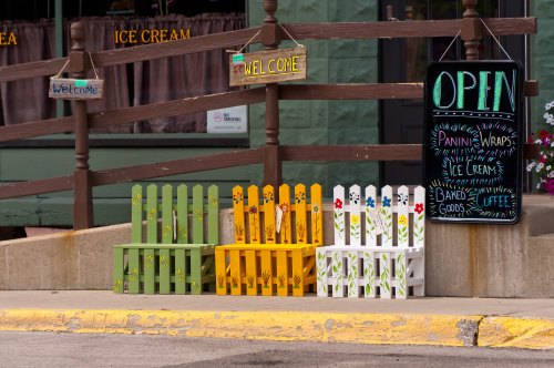 Colorful wooden crates in front of a shop, with a chalkboard sign advertising ice cream, baked goods, and coffee.
